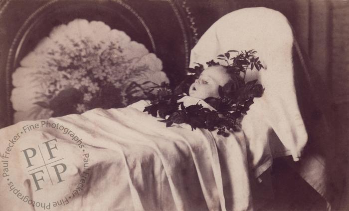 Baby with a wreath of dark leaves