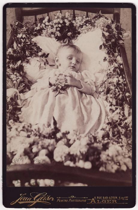 Child in a flower-strewn cot