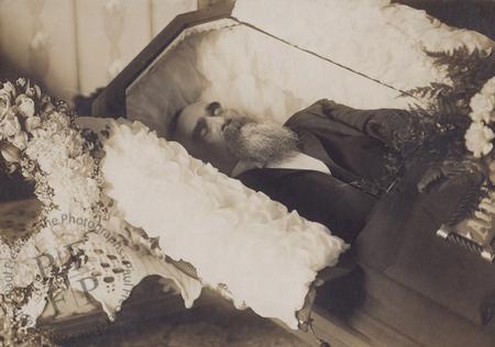 Bearded man in an open half-couch casket